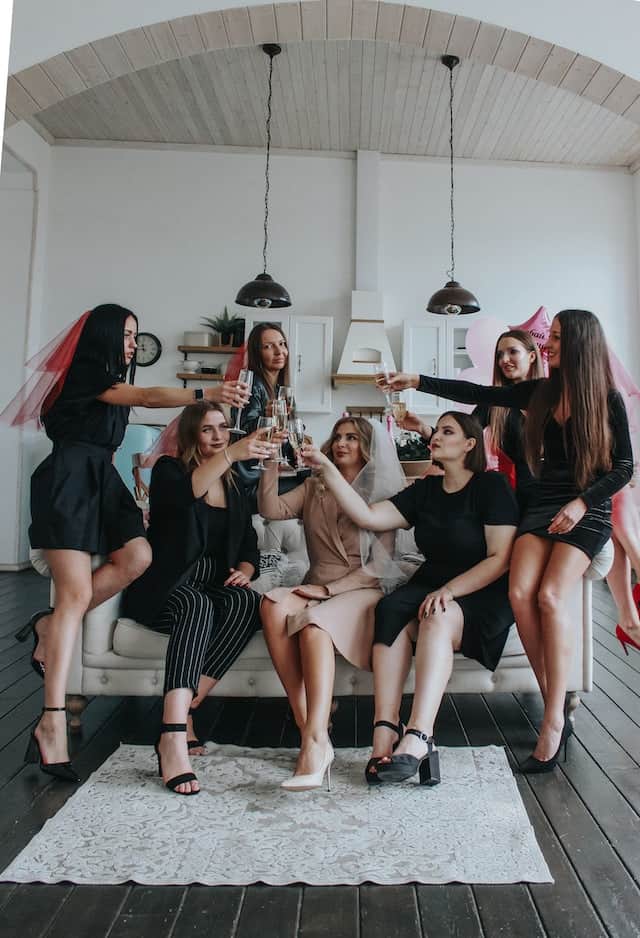 Junggesellenabschied Frauen mit kleinem Schleier feiern im Wohnzimmer 