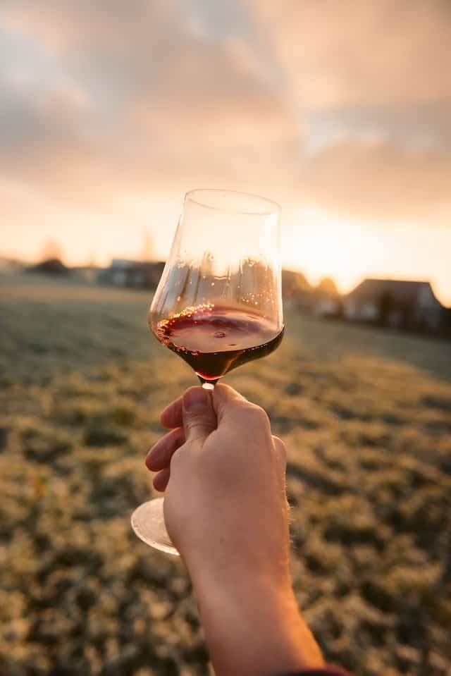 Glas mit Rotwein mit Sonnenuntergang im Hintergrund 