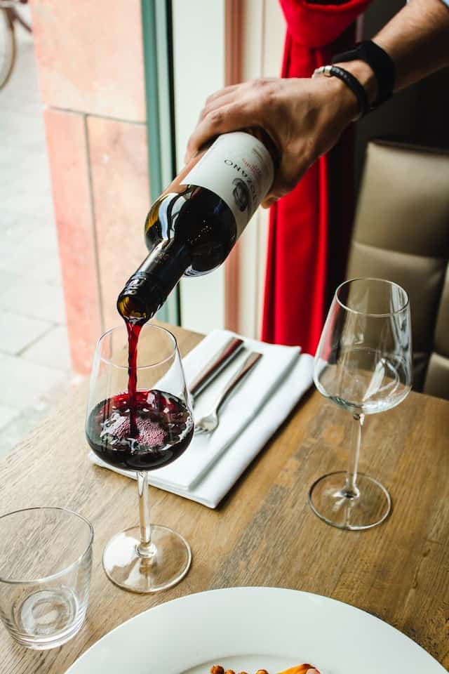 Wein einschenken: Rotwein wird im Restaurant eingeschenkt 